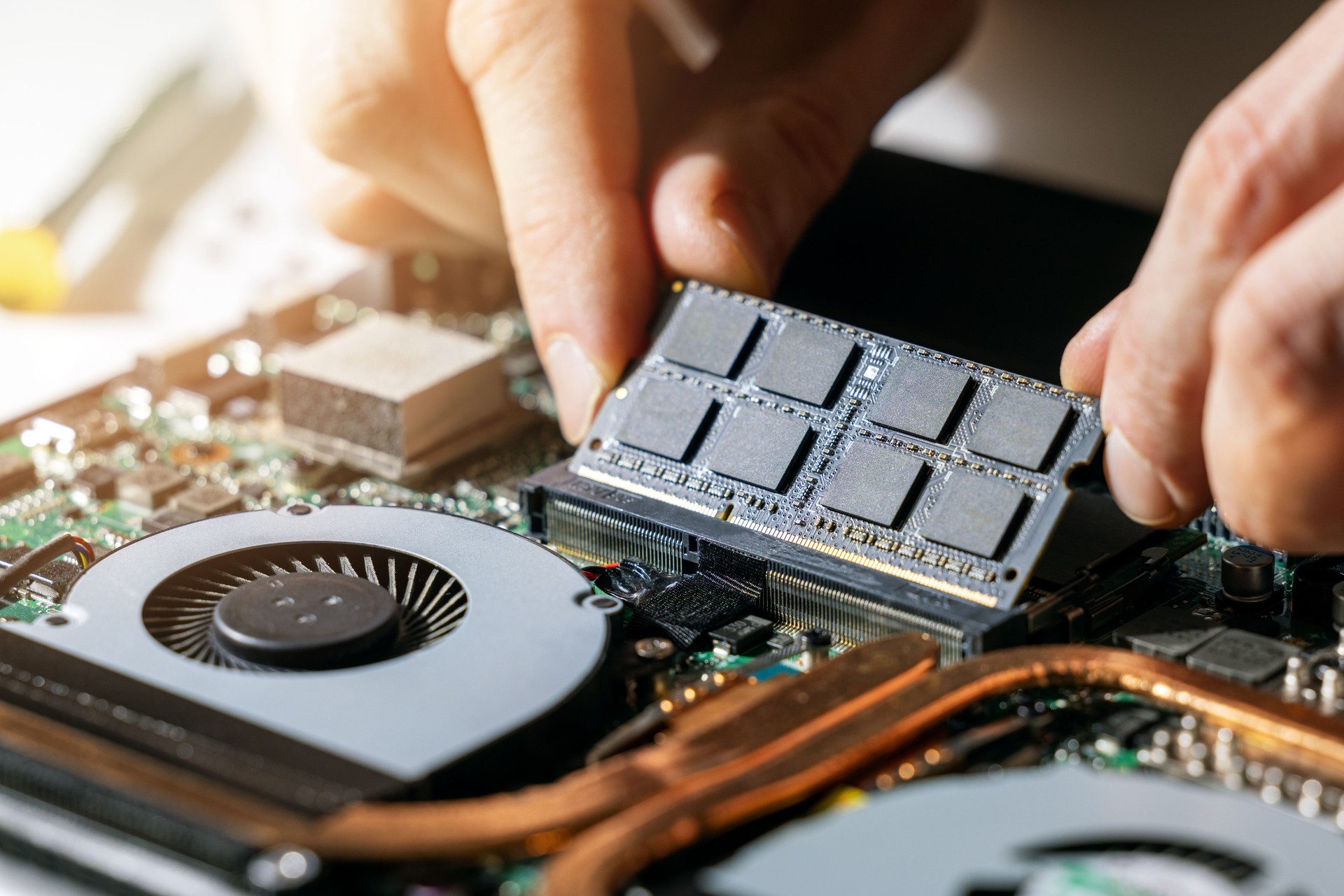 technician installing ram memory module in laptop motherboard. computer upgrade