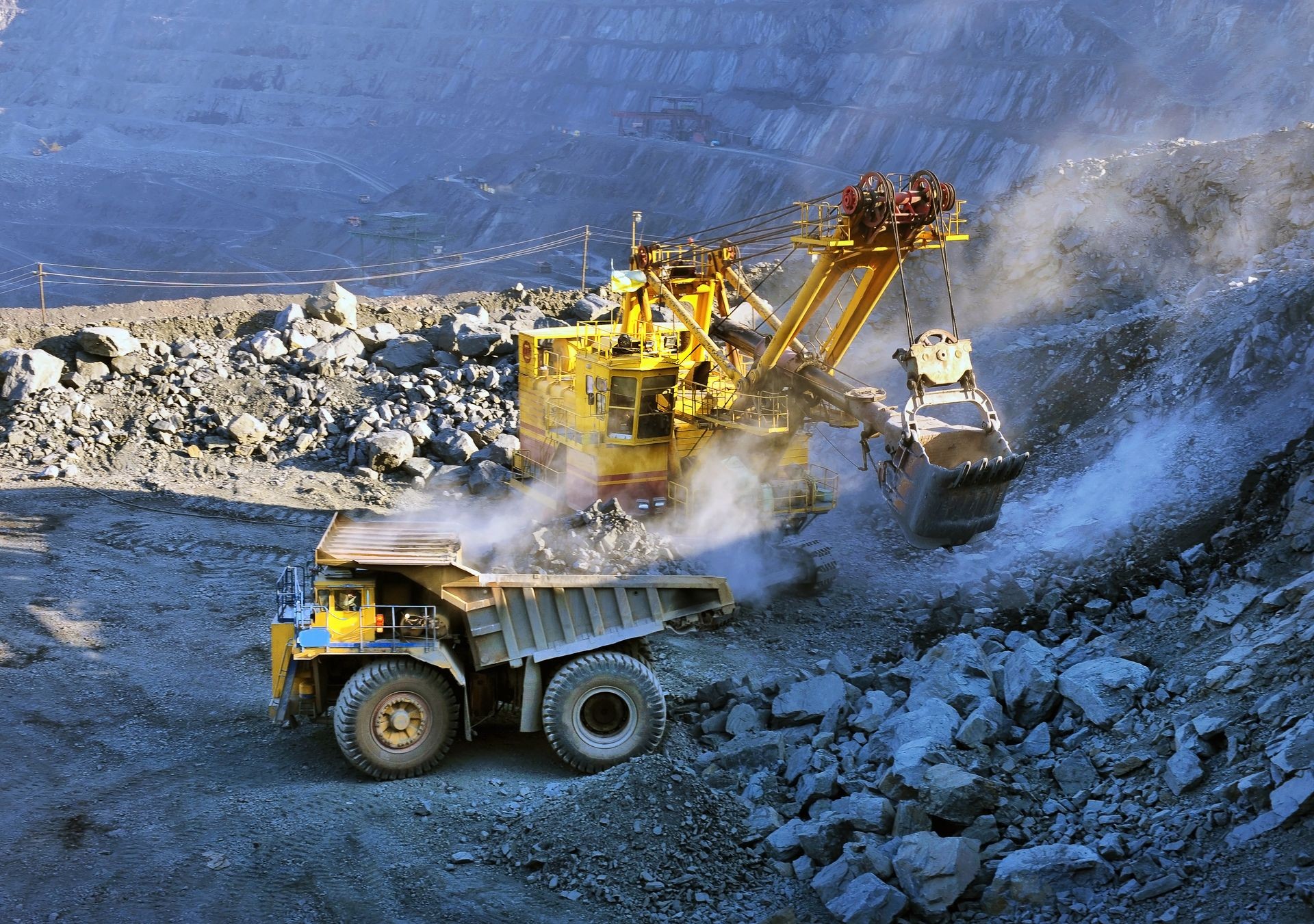 Excavator loading iron ore into heavy dump trucks on the opencast mining site